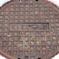 Square frame Rusty circular utility electric manhole cover amid fresh white snow in winter Royalty Free Stock Photo