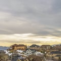 Square frame Scenic winter view of houses on a snowy mountain against cloudy sky at sunset