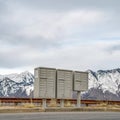 Square frame Selective focus mailboxes beside a road against snowy mountain and cloudy sky