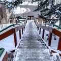 Square frame Stairway and road on snow covered hill amid houses and coniferous trees