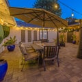 Square frame Stone patio with seating area under a gazebo and dining area under an umbrella