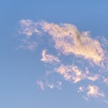 Square frame Wispy white clouds tinged pink at sunset