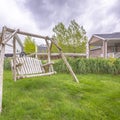Square frame Wooden bench swing at the lush grassy yard of a home with white picket fence