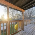 Square frame Wooden deck of house with yellow slide going down to the yard with trampoline