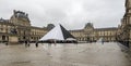 A square in front of Louvre museum with a large pyramid and visitors at the entrance, Paris