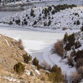 Square Frozen lake and hills blanketed with snow under cloudy blue sky in winter Royalty Free Stock Photo