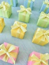 Square gift boxes in rainbow light gradient colors are neatly arranged on a blue-green watercolor textured background