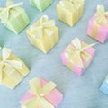 Square gift boxes in rainbow light gradient colors are neatly arranged on a blue-green watercolor textured background Royalty Free Stock Photo