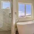 Square Glossy bathtub and separate shower inside the sunlit bathroom of a new house