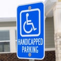 Square Handicapped Parking and Van Accessible sign against snow and building in winter Royalty Free Stock Photo