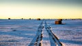 Square hay bales with tire tracks sit in a snow covered harvested field Royalty Free Stock Photo