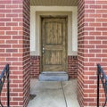 Square Home entrance with brown front door and metal furniture at the elevated porch Royalty Free Stock Photo