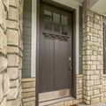 Square Home entrance with a glass paned brown wooden door and stone brick wall