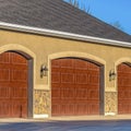 Square Home exterior with brown wooden garage doors against blue sky on a sunny day