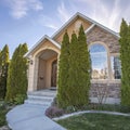 Square Home exterior with stone wall and pathway leading to the arched entry and door