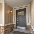 Square Home facade with a glass paned front door and stone brick and wooden wall