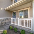 Square Home facade with small porch and blue gray front door with green leafy wreath