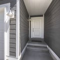 Square Home facade with view of the white front door and garage door on a sunny day