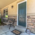 Square Home with green door yard windows and porch bench against stone brick wall Royalty Free Stock Photo