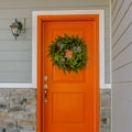 Square Home with a welcoming wreath hanging on the orange front door