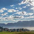 Square Houses by a lake with distant mountain and cloudy sky overhead on a sunny day