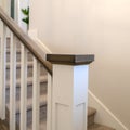 Square Indoor staircase of a home with white balusters brown handrail and newel