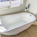 Square Interior of a bathroom with a smooth and glossy bathtub in th corner