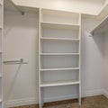 Square Interior of a walk in closet with shelves and shiny garment rods