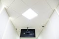 A square lamp and an advertising monitor on a white office ceiling. Round video surveillance lamps in the bank. Interior design in