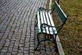 Square with metal benches in a row. The square is paved with gray granite cubes. green bench with metal decorative fittings. lawn Royalty Free Stock Photo