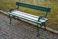 Square with metal benches in a row. The square is paved with gray granite cubes. green bench with metal decorative fittings. lawn