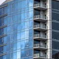 Square Moden building with glass walls and balconies viewed against cloudy blue sky