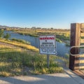 Square No Jumping Warning sign at a shallow lake with trails and bridge on a sunny day