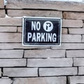 Square No Parking sign on a stone brick retaining wall topped with snow in winter Royalty Free Stock Photo