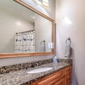 Square Oval sink on bathroom vanity countertop with cabinets and framed wall mirror