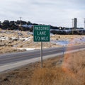 Square Passing Lane sign at the grassy side of road against snowy hill and cloudy sky