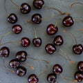 Square pattern made of ripe red cherries with stalks lying on dark grey stone textured background. Photo Royalty Free Stock Photo