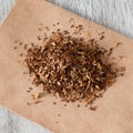 A square photo of dried sliced tobacco or a smoking drug mixture. Smoking drugs on paper close-up on a wooden table Royalty Free Stock Photo