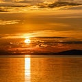 Square photo of Sunset over Umea river Mountains, summer sky with clouds highlighted by orange red Sun. Sunlight path on water Royalty Free Stock Photo