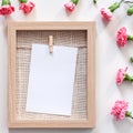 A square photo of a wooden mockup frame with a natural jute filling surrounded by pink flowers