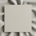 A square piece of textured light-gray paper is placed over a background of elegantly draped white Royalty Free Stock Photo