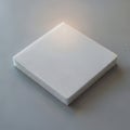 A square piece of white foam material rests on a smooth gray surface Royalty Free Stock Photo