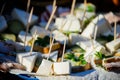 Square pieces of white homemade cheese on the wooden stick canape