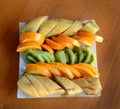 In a square plate sliced tropical fruits - bananas, kiwi, orange