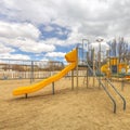 Square Playground with slides and swings under the blue sky filled with puffy clouds