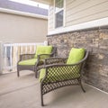 Square Porch armchairs against brick wall of a home with blue front door