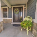 Square Porch and facade of home decorated with colorful flowers and wreath on the door