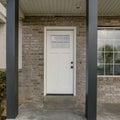 Square Porch of a house with black column posts and white front door with glass panel