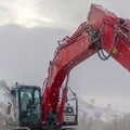 Square Red excavator and barricade on a muddy mountain road viewed in winter Royalty Free Stock Photo