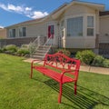 Square Red metal bench on the front yard of a home against blue sky on a sunny day Royalty Free Stock Photo